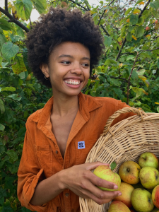 Poppy Okotcha smiling and holding a basket of apples.
